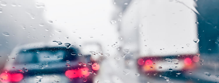 a car driving next to a truck in rainy weather that is one of the causes of trucking accidents