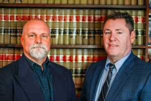 Attorneys Aaron Luck and Jim Bodin standing in front of a bookcase